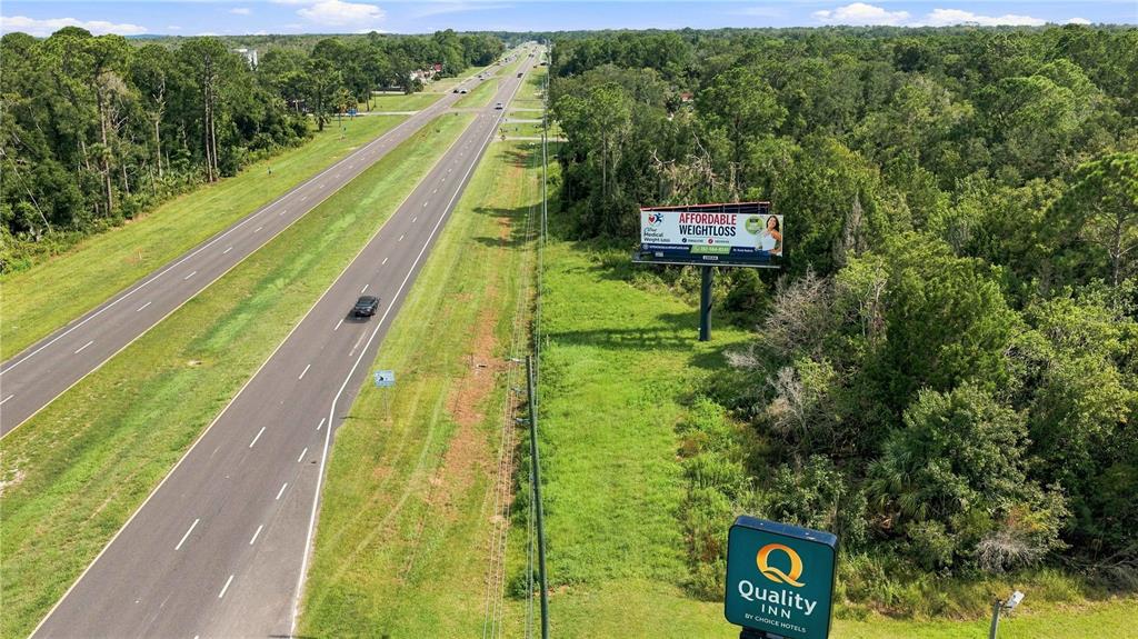 An aerial view shows a highway running alongside a wooded area with a billboard and sign — 4366 N SUNCOAST BOULEVARD, CRYSTAL RIVER, FL