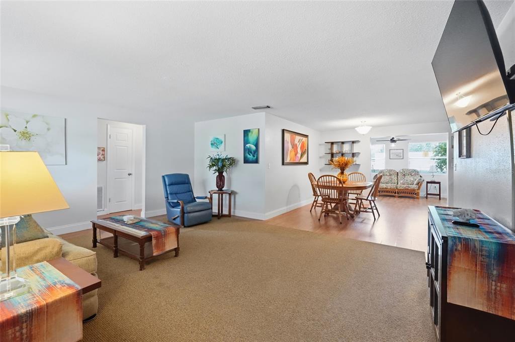 A living room features a blue recliner, a television, and a view into the kitchen — 5008 27TH AVENUE W, BRADENTON, FL