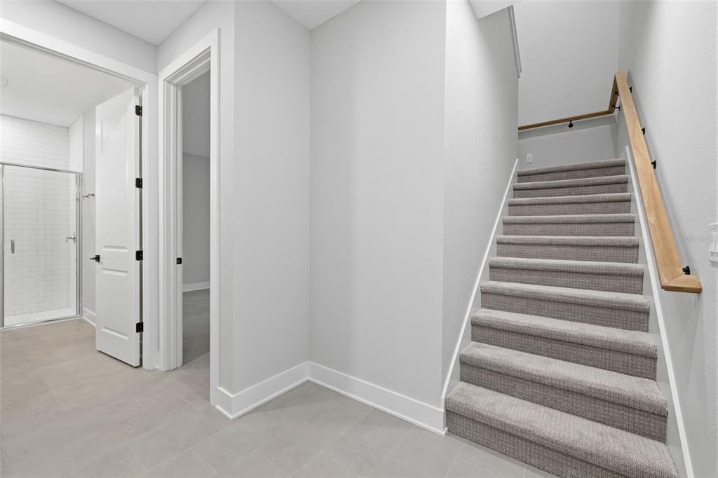 A staircase with gray carpet and a wooden handrail sits beside a tiled hallway — 4208 W CARMEN STREET UNIT B, TAMPA, FL