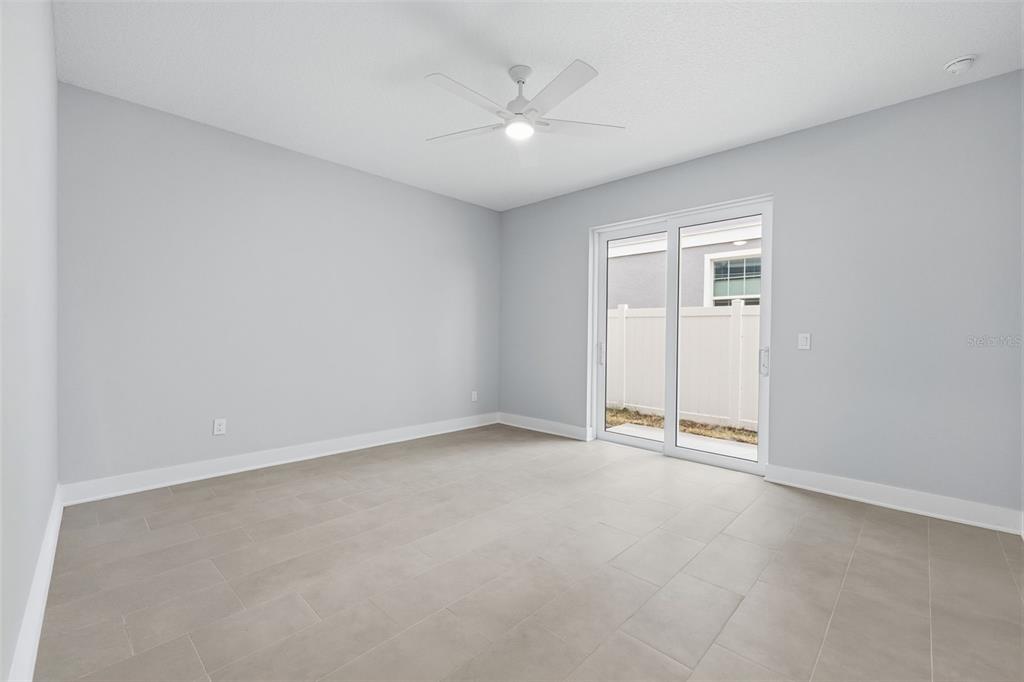 An empty room with light gray walls, tile flooring, a ceiling fan, and sliding glass doors — 4208 W CARMEN STREET UNIT B, TAMPA, FL