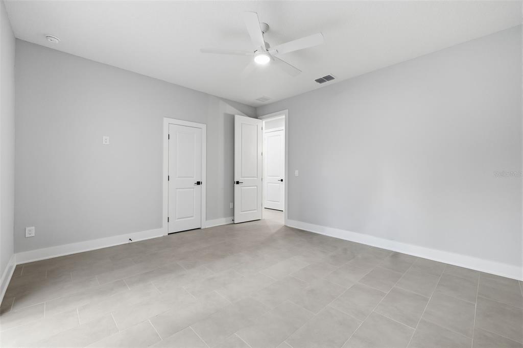 An empty bedroom with light gray walls, tile flooring, a ceiling fan, and two white doors — 4208 W CARMEN STREET UNIT B, TAMPA, FL