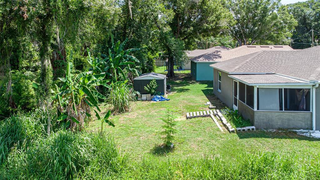 An aerial view shows a grassy backyard with a small shed and a house exterior — 151 1ST STREET, WINTER HAVEN, FL