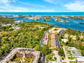 An aerial view shows a multi-story apartment complex near a coastal waterway and trees — 12760 INDIAN ROCKS ROAD UNIT 903, LARGO, FL