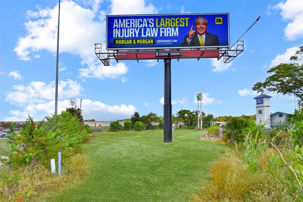A large billboard for a law firm stands in a grassy field under a blue sky — BLANDING BOULEVARD, JACKSONVILLE, FL