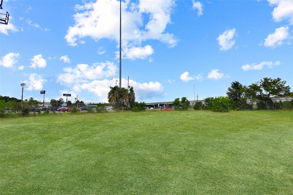 A large, grassy vacant lot sits under a blue sky with scattered clouds — BLANDING BOULEVARD, JACKSONVILLE, FL