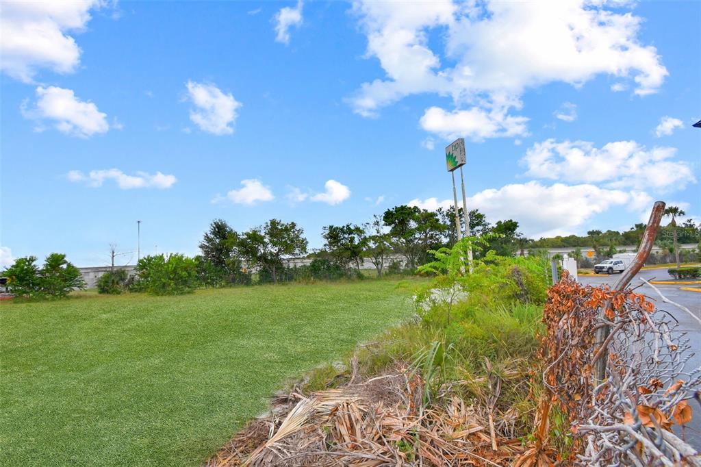 A grassy vacant lot features a BP gas station sign and a chain-link fence — BLANDING BOULEVARD, JACKSONVILLE, FL