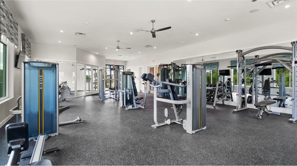 A bright fitness center features various Matrix exercise machines, rubber flooring, and large wall mirrors — 6088 MEDITATION DRIVE, CLERMONT, FL