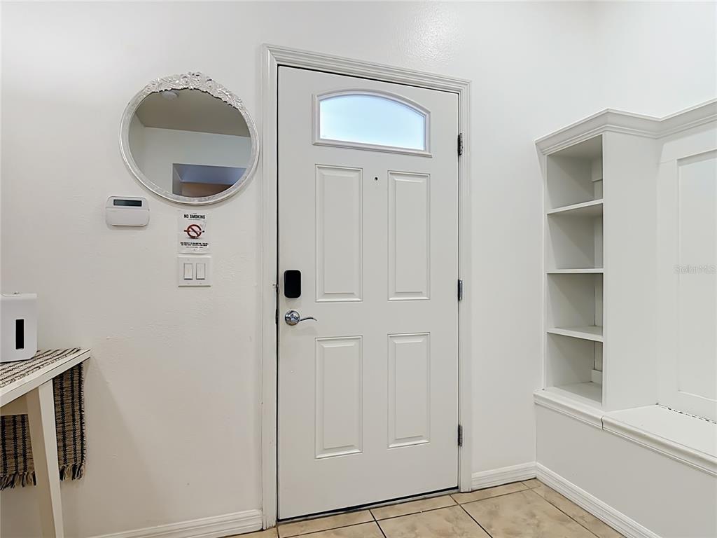 An entryway features a white door, a round mirror, and built-in shelving with a bench — 8891 GENEVE COURT, KISSIMMEE, FL