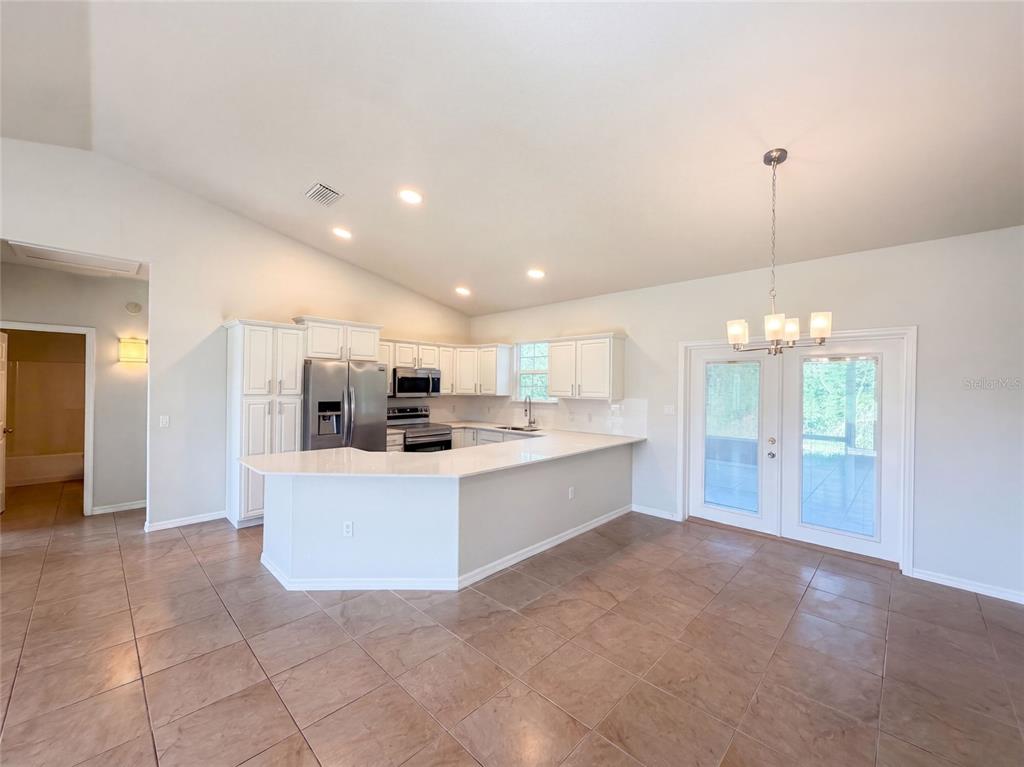 A kitchen with white cabinets, stainless steel appliances, and a peninsula island on tile flooring — 2925 N LOWELL ROAD, AVON PARK, FL