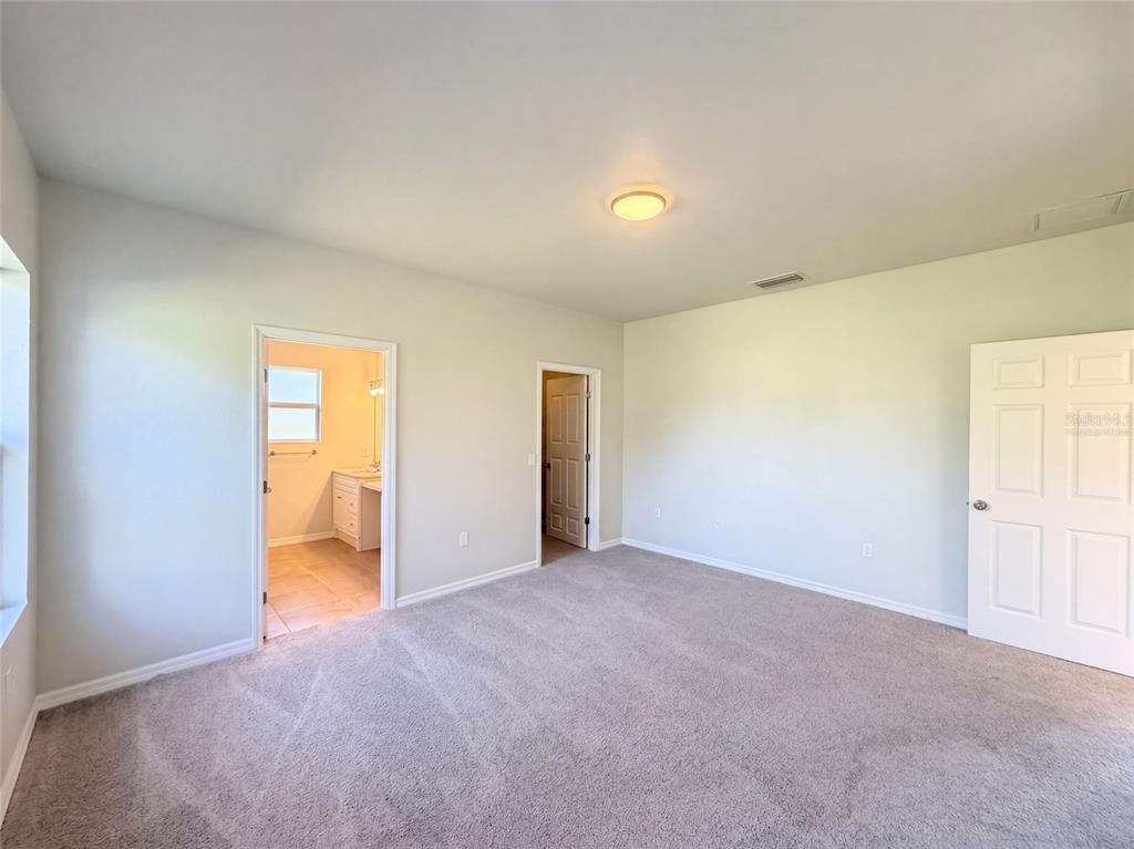 A bedroom with beige carpet, light-colored walls, a ceiling light, and two doorways — 2925 N LOWELL ROAD, AVON PARK, FL