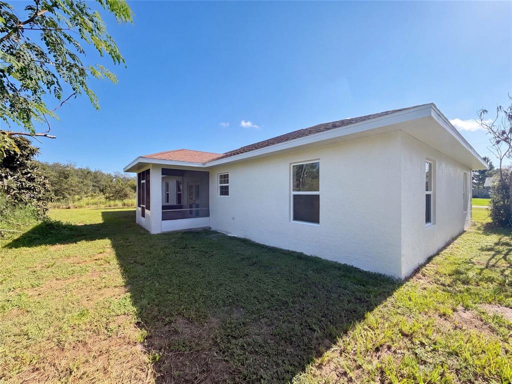 The exterior of a white house features a screened-in porch and a grassy backyard — 2925 N LOWELL ROAD, AVON PARK, FL
