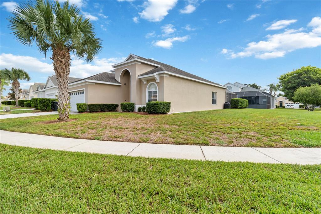 A single-story suburban house with a tan stucco exterior, a palm tree, and a lawn — 8160 SUN PALM DRIVE, KISSIMMEE, FL
