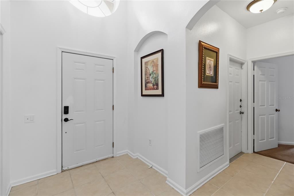 A bright entryway features a white front door, tiled floors, and two framed wall pictures — 8160 SUN PALM DRIVE, KISSIMMEE, FL