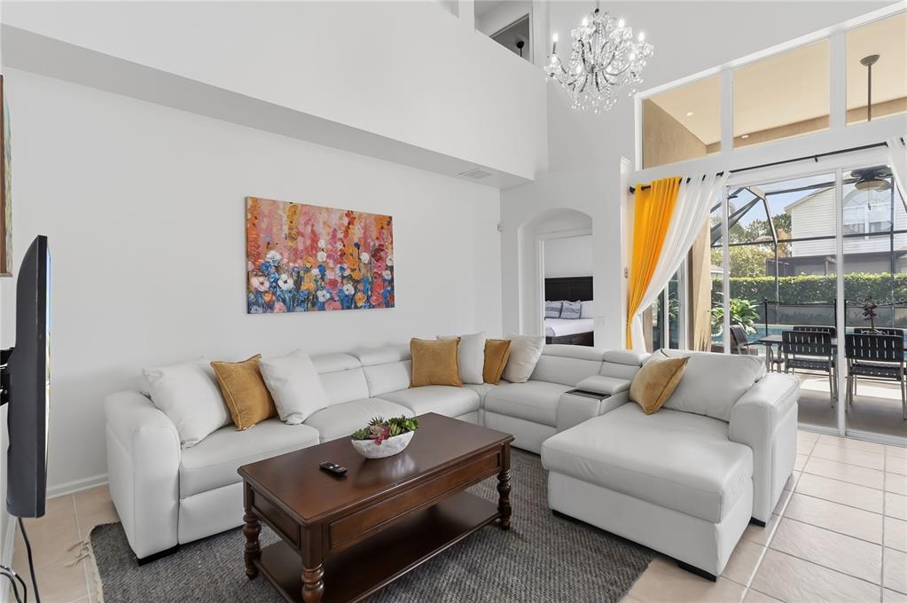 A living room features a white sectional sofa, a wooden coffee table, and a chandelier — 8160 SUN PALM DRIVE, KISSIMMEE, FL