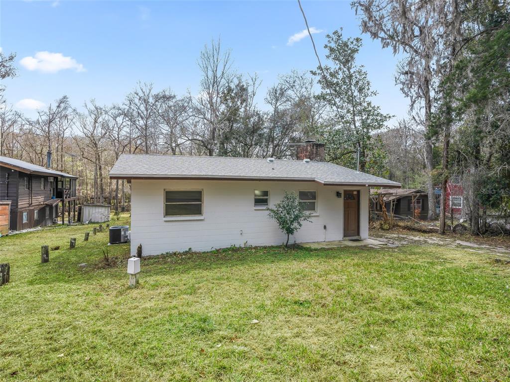 A white, single-story house with a brown door and a chimney sits on a grassy lot — 8935 CR 647S, BUSHNELL, FL
