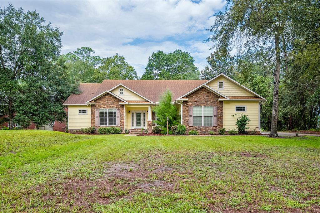 A single-story house with stone and yellow siding, a brown roof, and a grassy yard — 486 LAKESHORE DRIVE, STARKE, FL