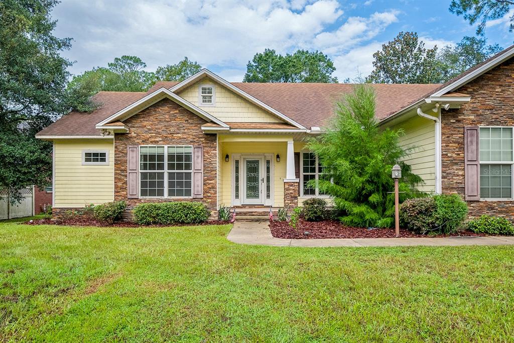 A single-story house with stone and yellow siding, a front porch, and a grassy lawn — 486 LAKESHORE DRIVE, STARKE, FL