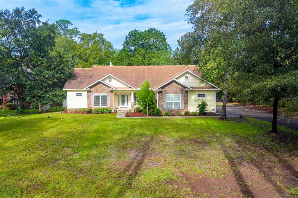 A single-story house with yellow siding, stone accents, and a large front lawn — 486 LAKESHORE DRIVE, STARKE, FL