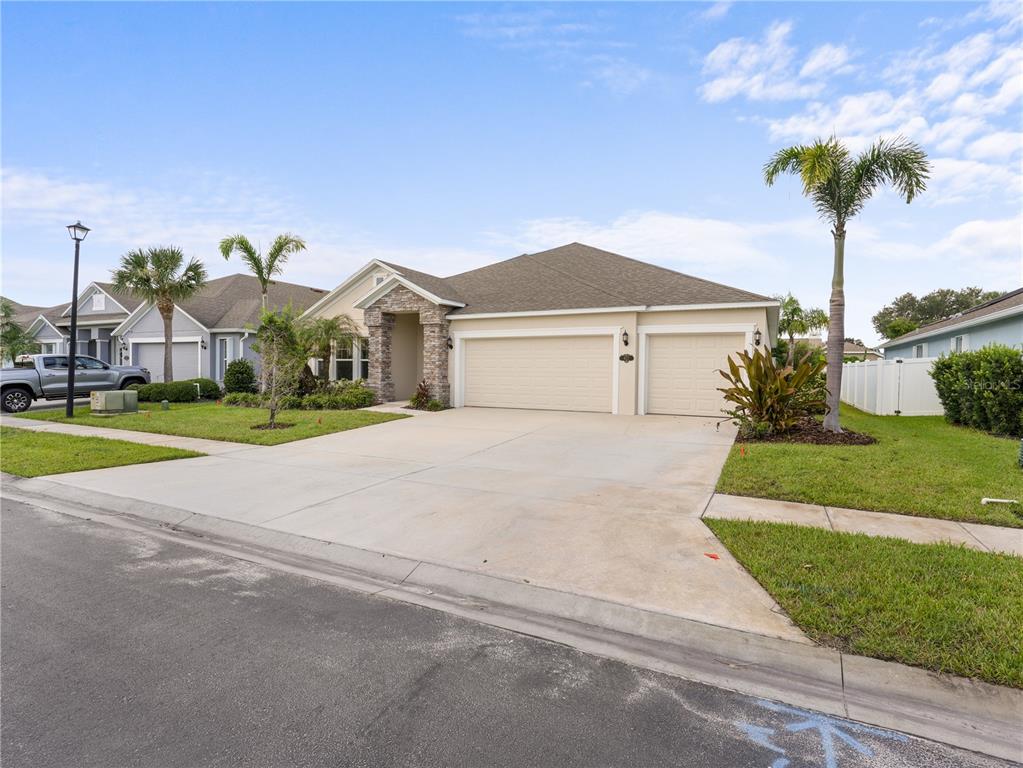 A single-story house with a three-car garage, stone accents, and palm trees in the front yard — 4212 RUTHANN CIRCLE, MELBOURNE, FL