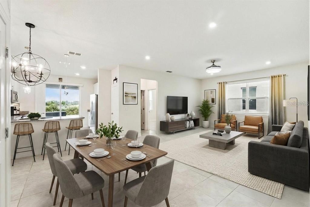 An open-concept living and dining area with tile floors, a kitchen island, and neutral decor — 2282 NUTHATCH STREET, ST CLOUD, FL