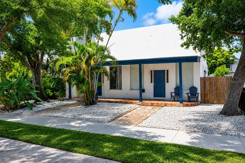 A single-story white house with a flat roof, two blue doors, and a dirt yard — 3651 HAINES ROAD N, ST PETERSBURG, FL