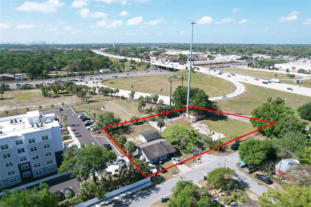An aerial view shows a fenced lot with a small house and a communication tower — 705 E WILMA STREET, TAMPA, FL