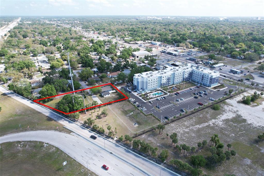 An aerial view shows a rectangular lot outlined in red next to a large apartment complex — 705 E WILMA STREET, TAMPA, FL