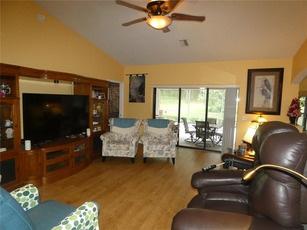 A living room features a large entertainment center, two patterned armchairs, and a leather recliner — 19443 SW 101ST PLACE ROAD, DUNNELLON, FL
