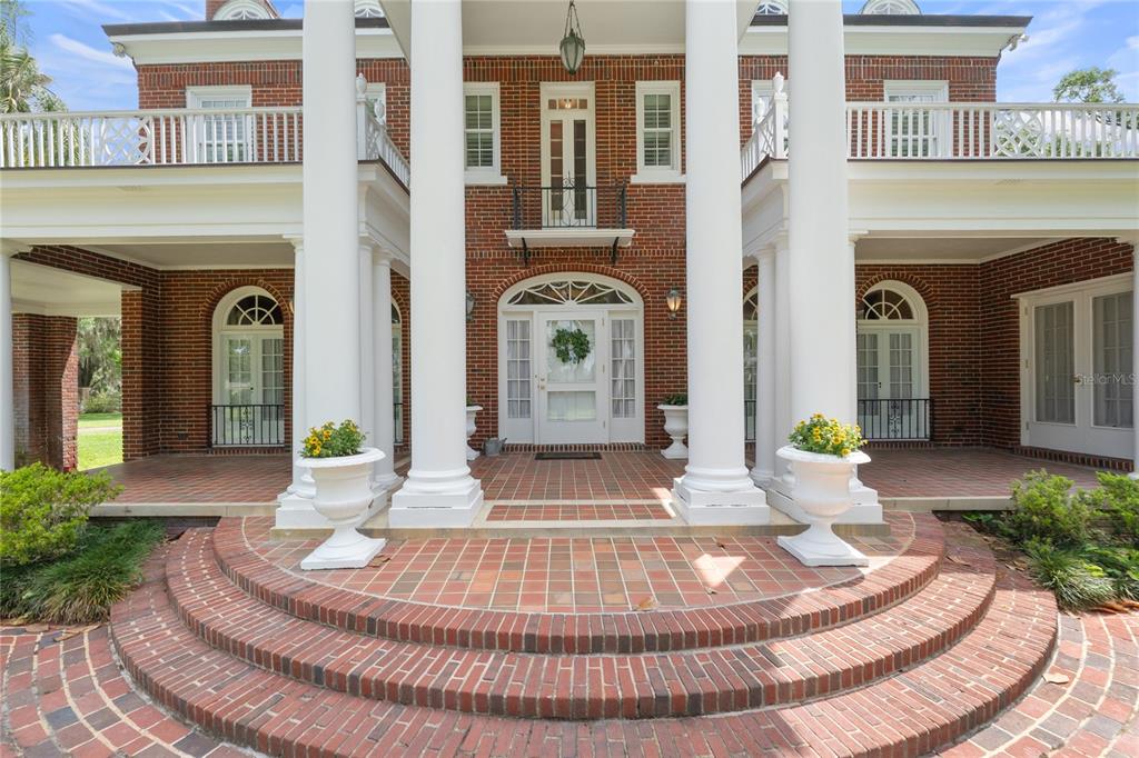 A brick house entrance features a white front door, a balcony, and large white columns — 1760 OLD EAGLE LAKE ROAD, BARTOW, FL