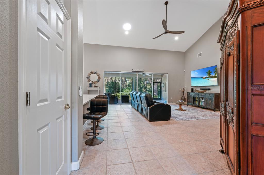 A spacious living room features tile flooring, a vaulted ceiling, a ceiling fan, and a patio — 5039 GREENBRIAR TRAIL, MOUNT DORA, FL