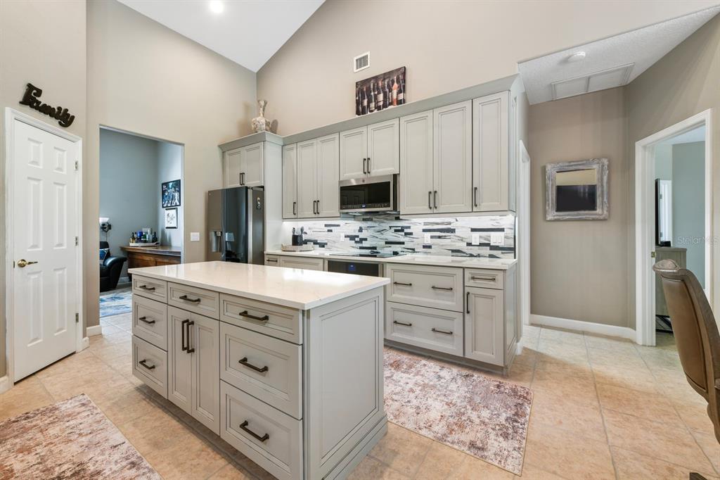 A kitchen with light gray cabinets, a white quartz island, and a patterned tile backsplash — 5039 GREENBRIAR TRAIL, MOUNT DORA, FL