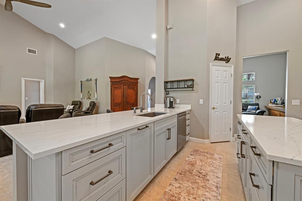 A kitchen features a large white quartz island, light gray cabinetry, and tile flooring — 5039 GREENBRIAR TRAIL, MOUNT DORA, FL