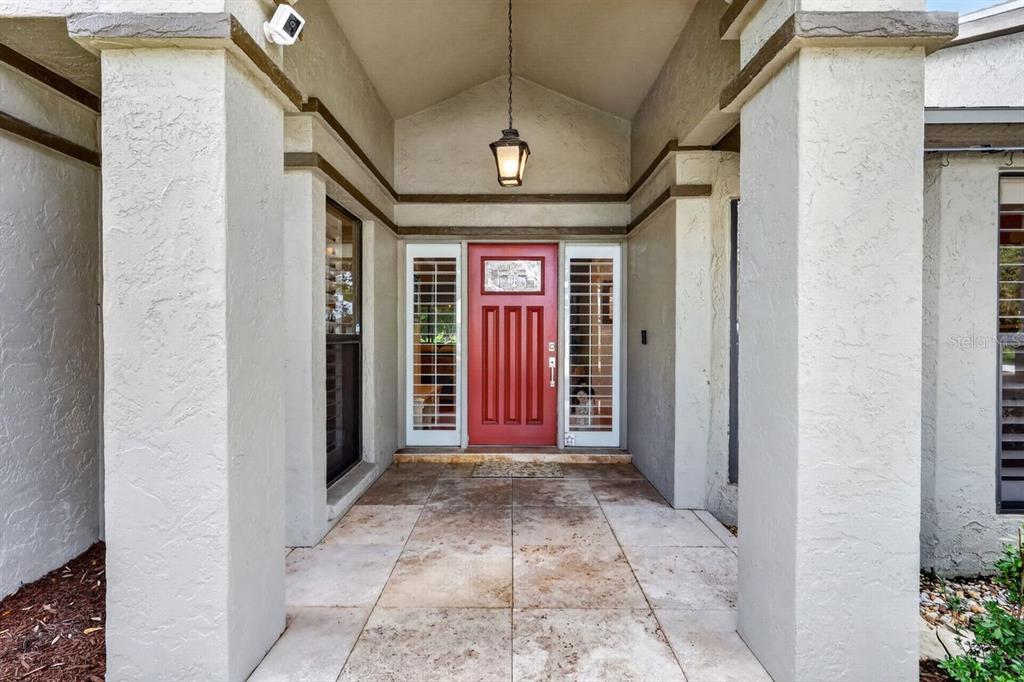 A covered entryway features a red front door with sidelights between two large stucco columns — 4395 OAK VIEW DRIVE, SARASOTA, FL
