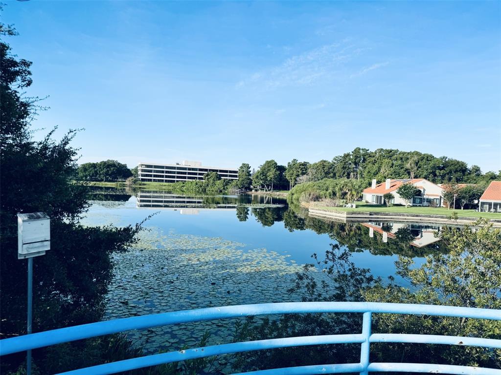 A view of a lake with lily pads, a large office building, and residential houses — 1000 WINDERLEY PLACE UNIT 128, MAITLAND, FL