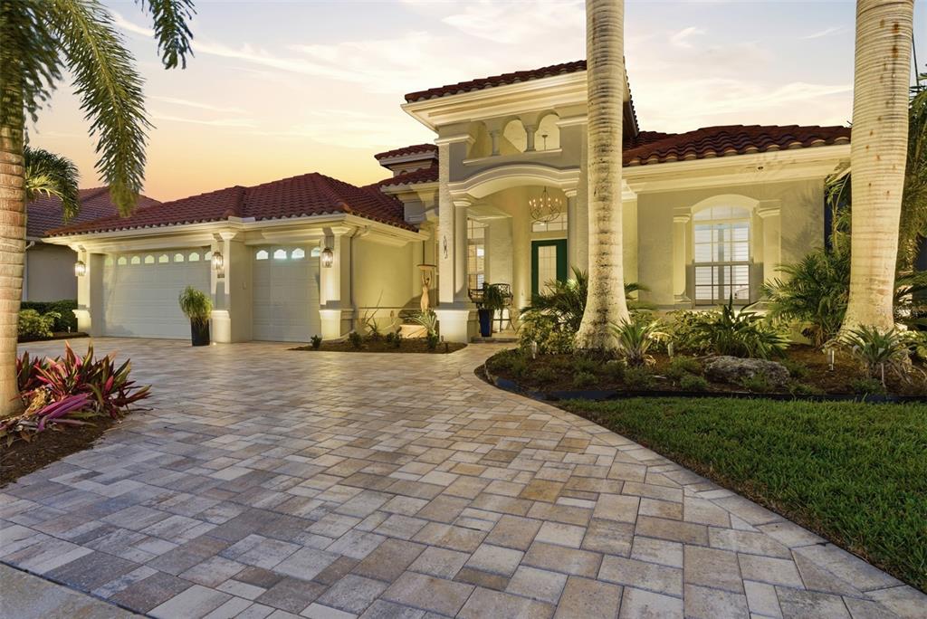 A single-story house with a tiled roof, a paved driveway, and palm trees at dusk — 120 12TH AVENUE E, PALMETTO, FL
