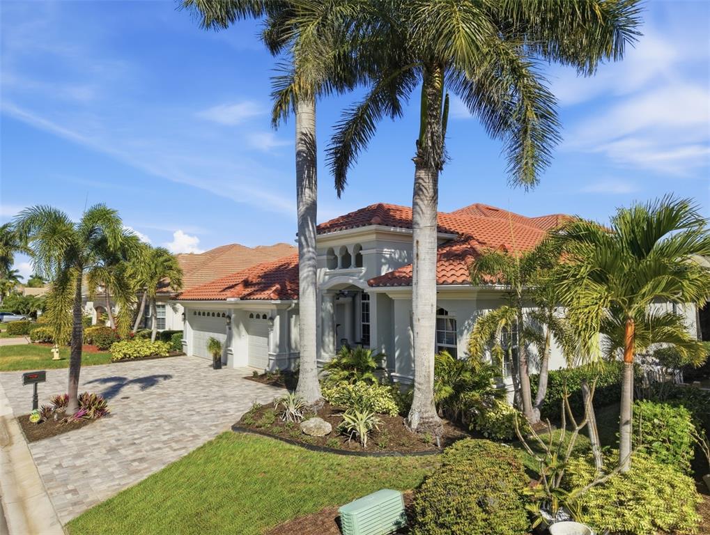A single-story house with a tile roof, paved driveway, and palm trees in the front yard — 120 12TH AVENUE E, PALMETTO, FL