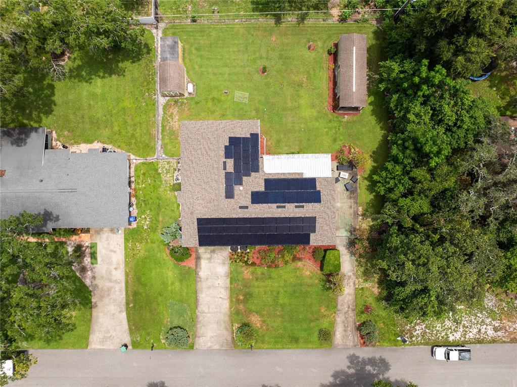 An aerial view shows a house with solar panels on the roof and a large yard — 1435 PAULA DRIVE, APOPKA, FL