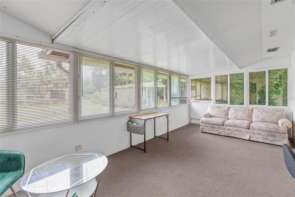 A sunroom with white walls, carpeted flooring, large windows with blinds, and a floral sofa — 1435 PAULA DRIVE, APOPKA, FL