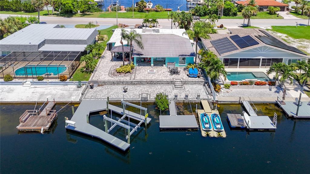 An aerial view shows three waterfront houses with private docks, pools, and paved patios — 3516 FLORAMAR TERRACE, NEW PORT RICHEY, FL