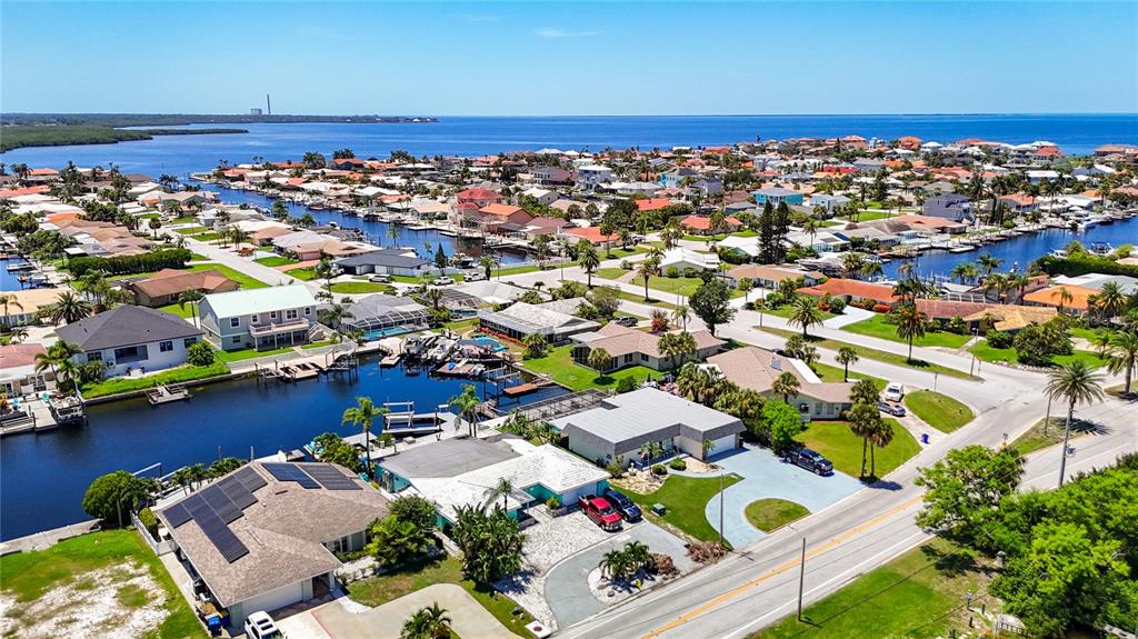An aerial view shows waterfront houses with boat docks along a canal near the ocean — 3516 FLORAMAR TERRACE, NEW PORT RICHEY, FL