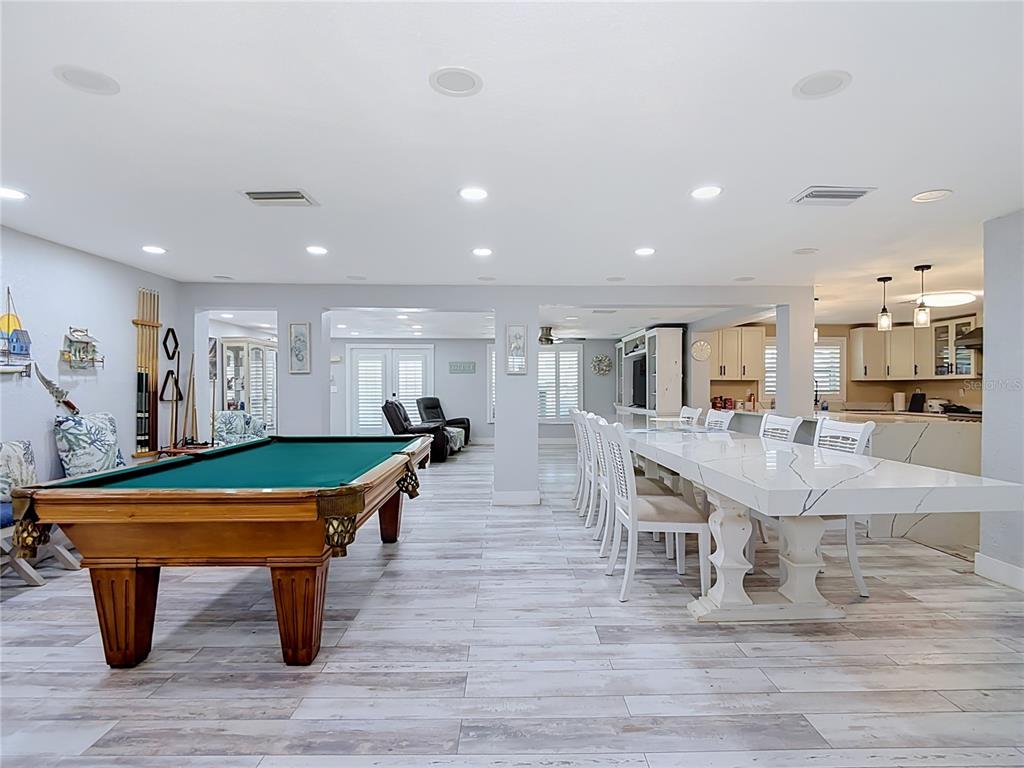 A large open-concept room features a pool table, a long dining table, and kitchen cabinetry — 3516 FLORAMAR TERRACE, NEW PORT RICHEY, FL