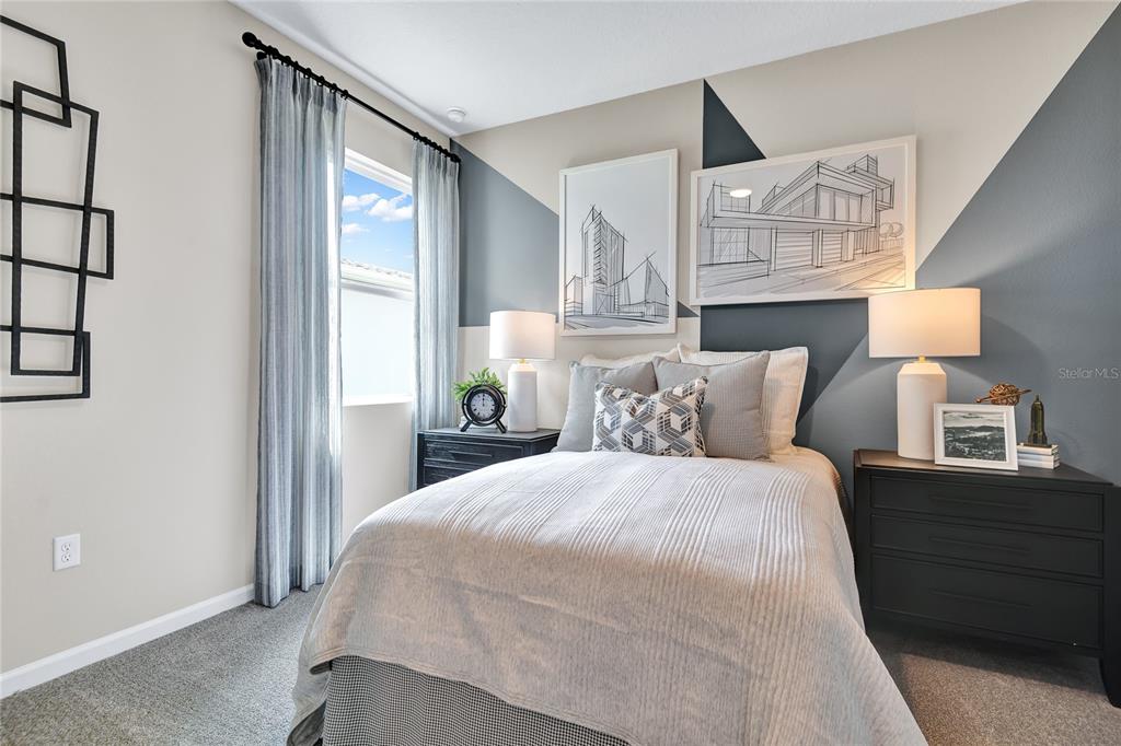 A bedroom features a bed between two nightstands, geometric wall paint, and framed architectural sketches — 1249 DAISY HILL AVENUE, DUNDEE, FL