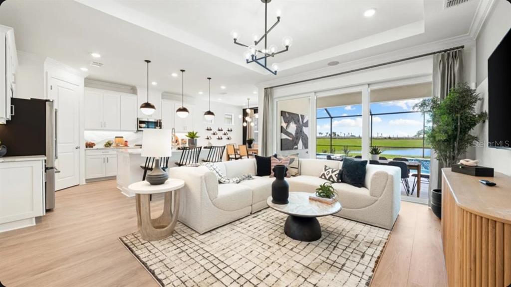 A modern white kitchen features a large marble-topped island with black bar stools — 7649 MOONBEAM AVENUE, SARASOTA, FL