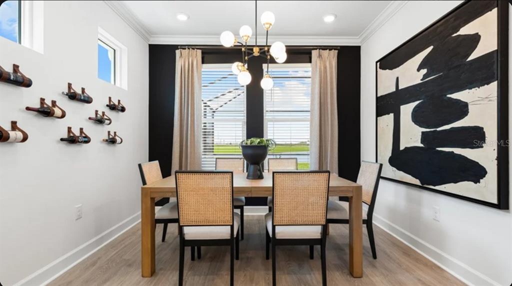A modern open-concept living room and kitchen feature white cabinetry, light wood flooring, and sliding doors — 7649 MOONBEAM AVENUE, SARASOTA, FL