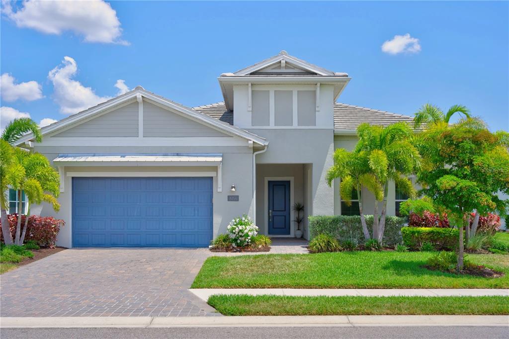 A single-story house with a blue garage door, a front entrance, and palm trees — 8154 REDONDA LOOP, LAKEWOOD RANCH, FL