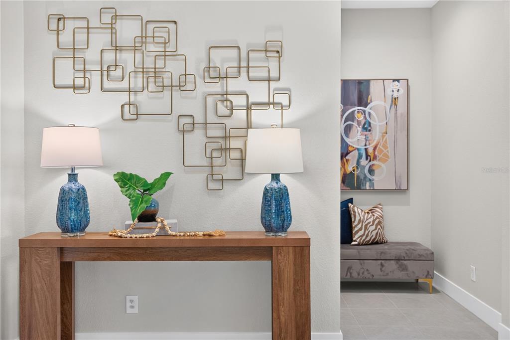 A wooden console table with two blue lamps sits below gold metal wall art — 8154 REDONDA LOOP, LAKEWOOD RANCH, FL