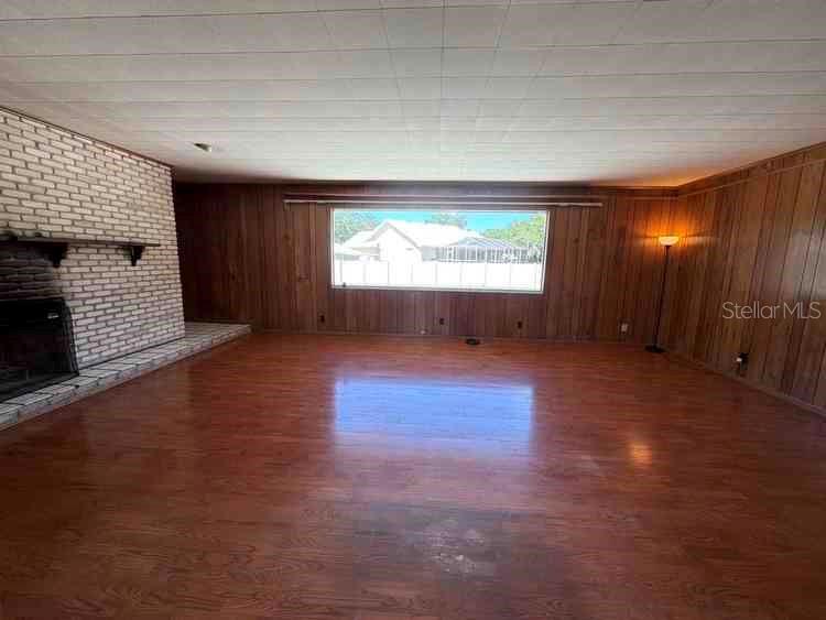 A living room features wood-paneled walls, a white brick fireplace, and wood-look flooring — 3355 WILLIS ROAD, MULBERRY, FL