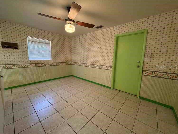 A room with tiled floors, wallpaper, a ceiling fan, and a green door — 3355 WILLIS ROAD, MULBERRY, FL