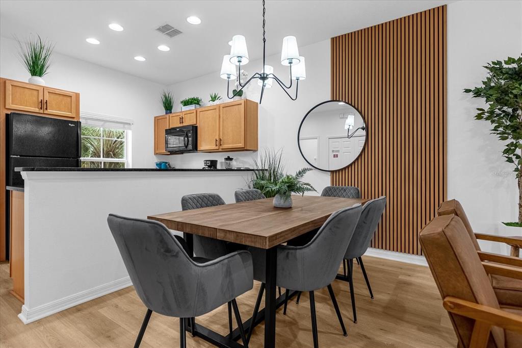 A dining area features a wooden table with gray chairs, a chandelier, and wood-slat wall paneling — 3054 YELLOW LANTANA LANE, KISSIMMEE, FL