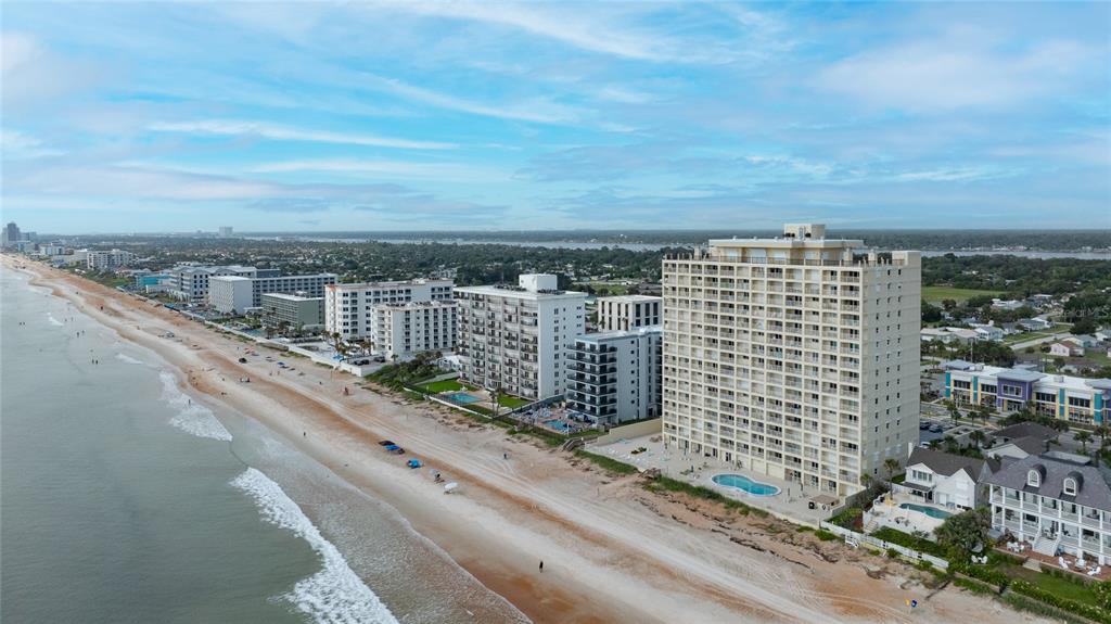 An aerial view of a sandy beach lined with several high-rise condominium buildings and homes — 89 S ATLANTIC AVENUE UNIT 1503, ORMOND BEACH, FL